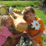 Ein Junge und ein Mädchen umarmen die Statue einer Kuh.