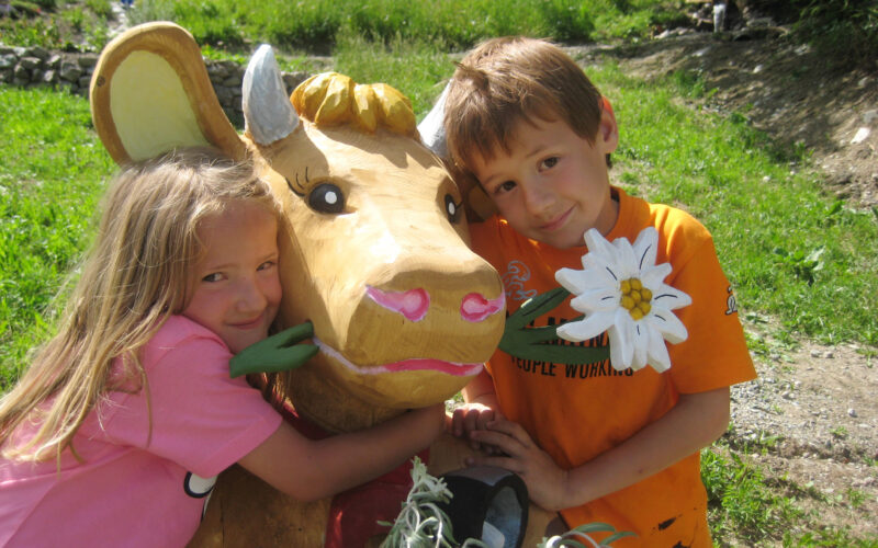 Ein Junge und ein Mädchen umarmen die Statue einer Kuh.
