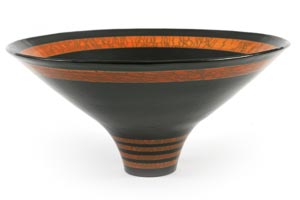 Eine breite, schwarze Keramikschale mit schmalem Sockel und orangefarbenen Zierbändern und -mustern am Rand und Boden.