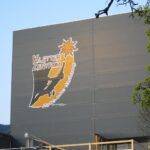 Ein graues Gebäude mit einem großen Schild mit der Aufschrift "Kletterzentrum" und der Abbildung eines Kletterers, eines Berges und einer Edelweißblume.