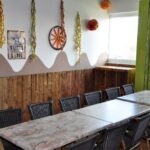 Ein langer Tisch mit schwarzen Stühlen in einem Raum, der mit Westernmotiven, bunten Luftschlangen und natürlichem Licht aus zwei Fenstern dekoriert ist.