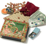 Ein altes Tombola-Spielset mit einer verzierten Schachtel, Spielkarten, kleinen nummerierten Holzplättchen, einem Beutel und anderen ausgestellten Spielfiguren.