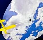Ein gelbes Modellflugzeug hängt vor einer Himmelskulisse mit Wolken, die mit einem Stab an einem weißen wolkenförmigen Objekt befestigt ist.