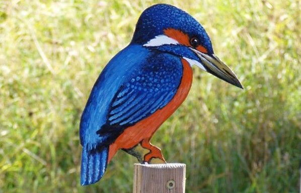 Ein realistisches Gemälde eines blauen und orangefarbenen Eisvogels auf einem Holzpfosten vor einem verschwommenen grünen Hintergrund.