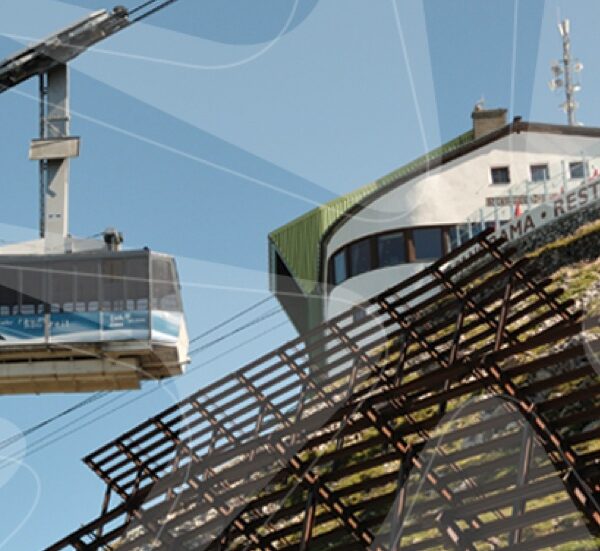 Eine Seilbahn fährt an einem klaren Tag zu einer Bergstation in der Nähe eines Gebäudes mit der Aufschrift "RESTAURANT".