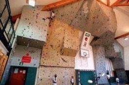 Eine Kletterhalle mit künstlichen Kletterwänden unterschiedlicher Höhe und einem Basketballkorb an einer Wand.