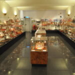 Ein gut beleuchteter Museumsraum mit Glasvitrinen, in denen verschiedene Vintage-Artikel, hauptsächlich kleine Schachteln und Sammlerstücke, ordentlich an den Wänden und in der Mitte angeordnet sind.