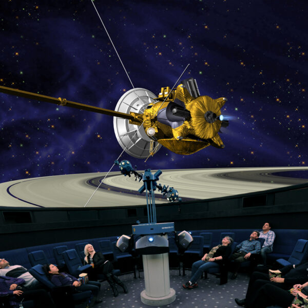 Die Besucher eines Planetariums sehen auf einem großen Kuppelbildschirm die Projektion eines Raumschiffs in der Nähe des Saturns und seiner Ringe.