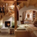 Der gemütliche, rustikale Wohnbereich verfügt über Holzbalken, einen Kamin, eine Küchenzeile, sanfte Beleuchtung und plüschige Sitzgelegenheiten mit Schafsfell-Akzenten.