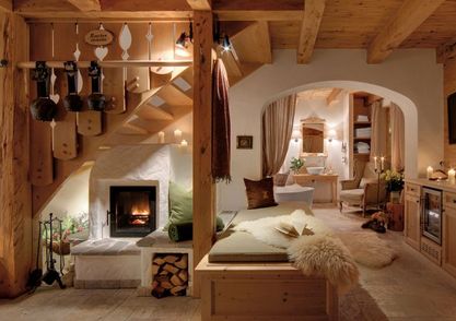 Der gemütliche, rustikale Wohnbereich verfügt über Holzbalken, einen Kamin, eine Küchenzeile, sanfte Beleuchtung und plüschige Sitzgelegenheiten mit Schafsfell-Akzenten.