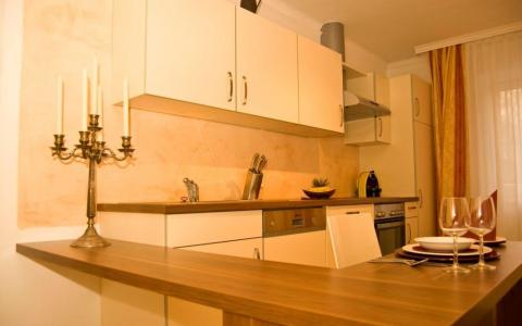 Moderne Küche mit hellen Schränken, einer Arbeitsplatte aus Holz, Einbaugeräten, einem Kandelaber und einer Essecke mit Tellern und Weingläsern.