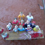 Eine Gruppe von Kindern steht um einen Tisch mit Medaillen und Bändern auf einem Tennisplatz, schaut auf und lächelt in die Kamera.