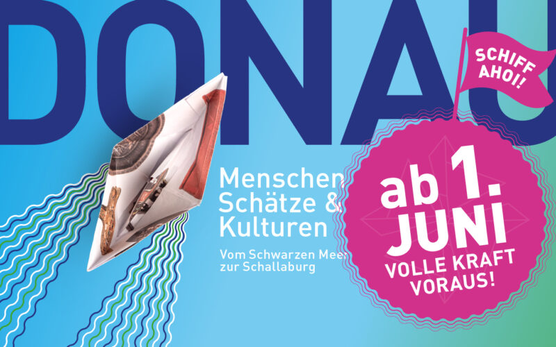 Grafisches Plakat mit einem Papierboot, großer blauer Schrift "DONAU" und einer rosa Sprechblase mit der Aufschrift "Schiff Ahoi!" Kündigt die Veranstaltung "ab 1. Juni" mit dem Thema "Menschen, Schätze & Kulturen.