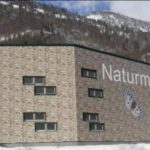Ein modernes Backsteingebäude mit der Aufschrift "Naturmuseum Treffpunkt Natur" und dem Bild eines Schmetterlings in einer verschneiten Berglandschaft.