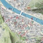 Illustrierter Stadtplan mit Straßen, Sehenswürdigkeiten und einem Fluss, der durch das Zentrum fließt, mit nummerierten Orten in der gesamten Region.