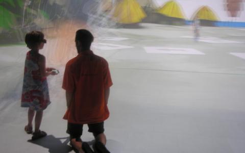 Ein Kind und ein Erwachsener, die beide eine 3D-Brille tragen, stehen bzw. knien in einer hell erleuchteten, verschwommenen Virtual-Reality-Umgebung.