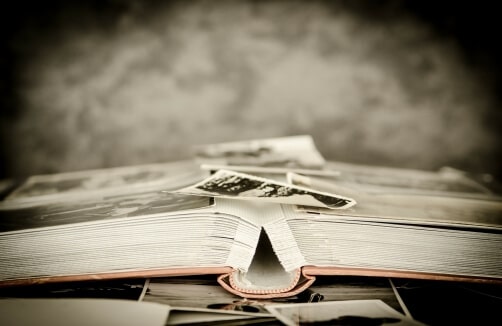 Ein aufgeschlagenes Fotoalbum mit mehreren losen Schwarz-Weiß-Fotos, die auf und um die Seiten verstreut sind.